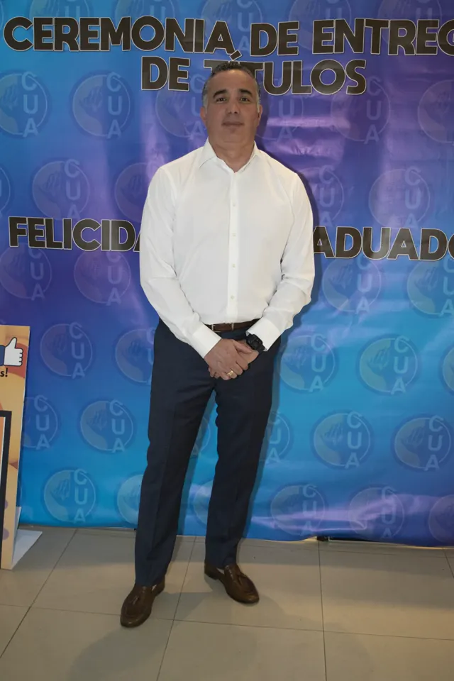 Graduado con camisa blanca frente al fondo de la ceremonia. Graduación del 7 de julio de 2025.