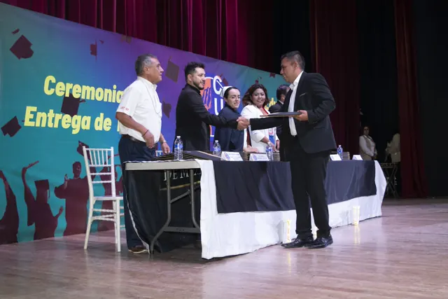 Graduado recibe su documento de manos de las autoridades. Graduación del 7 de julio de 2025.