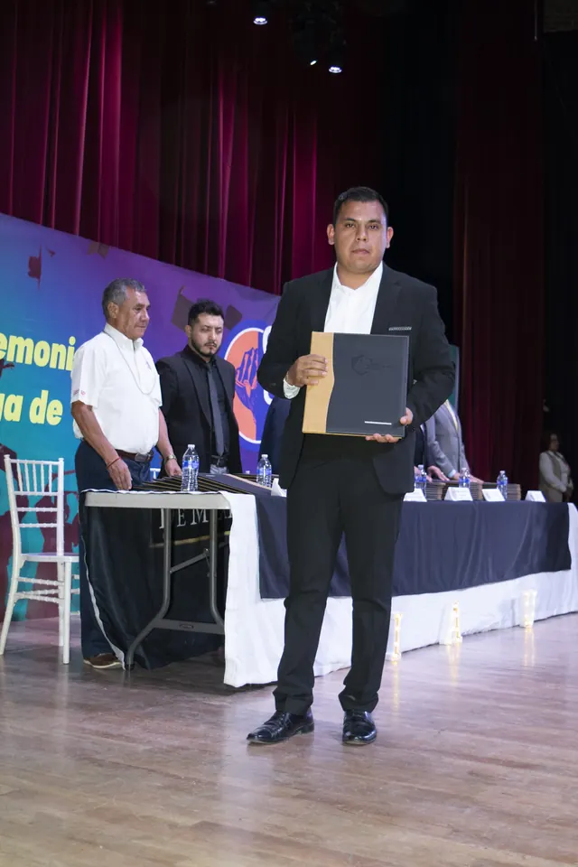 Graduado muestra su documento en el escenario. Graduación del 7 de julio de 2025.
