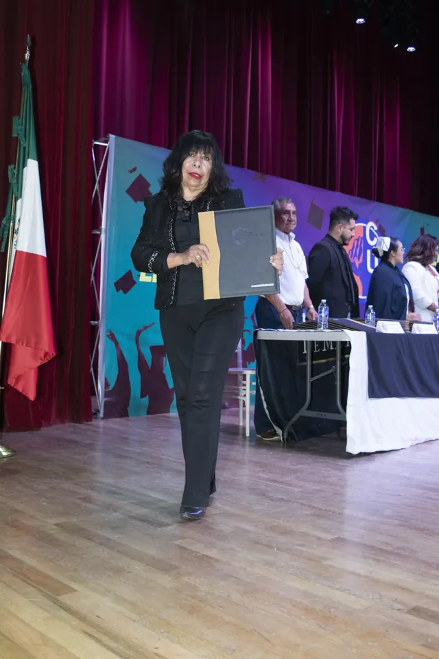 Graduada camina por el escenario con su documento. Graduación del 7 de julio de 2025.