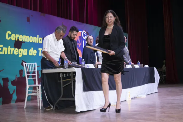 Graduada sonriente durante la entrega de su documento. Graduación del 7 de julio de 2025.