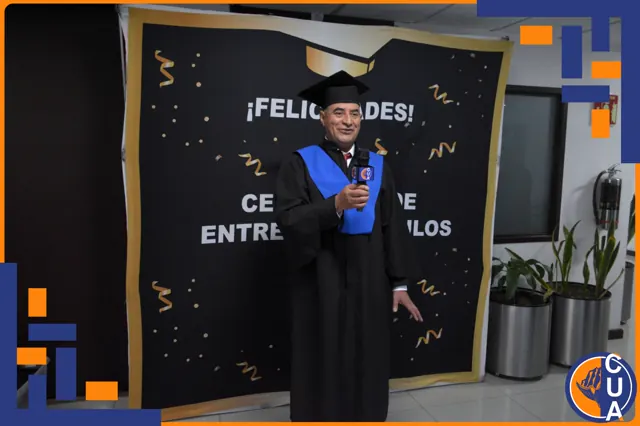 Graduado con toga negra y estola azul habla por un micrófono durante la ceremonia.