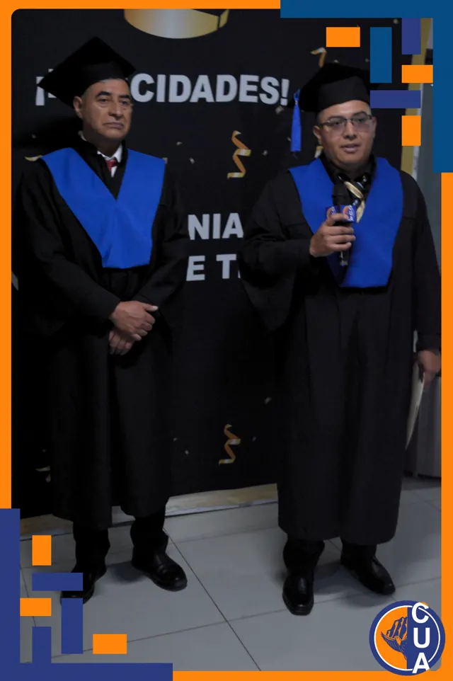 Dos graduados con toga y estola azul comparten un momento de la ceremonia; uno sostiene un micrófono.