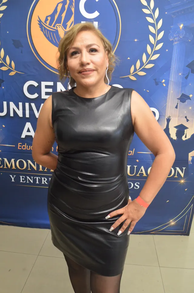 Participante sonriente con vestido negro posa con una mano en la cintura ante el fondo de Acacias.