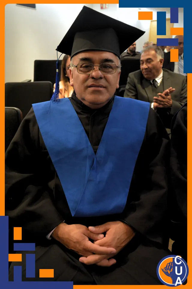 Graduado con toga, estola azul y anteojos se encuentra sentado en el auditorio. Graduación del 14 de junio de 2025.